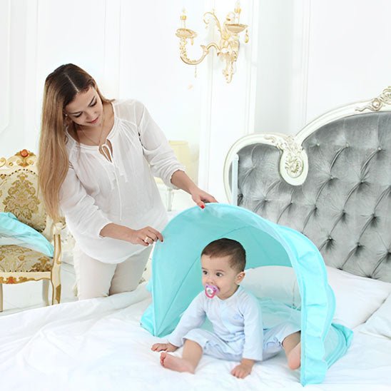 MOUSTIQUAIRE LIT BEBE | PROTECTION ULTRA-RESPIRANTE - TURQUOISE AVEC MAMAN QUI REGARDE BÉBÉ ASSIS SUR LE LIT